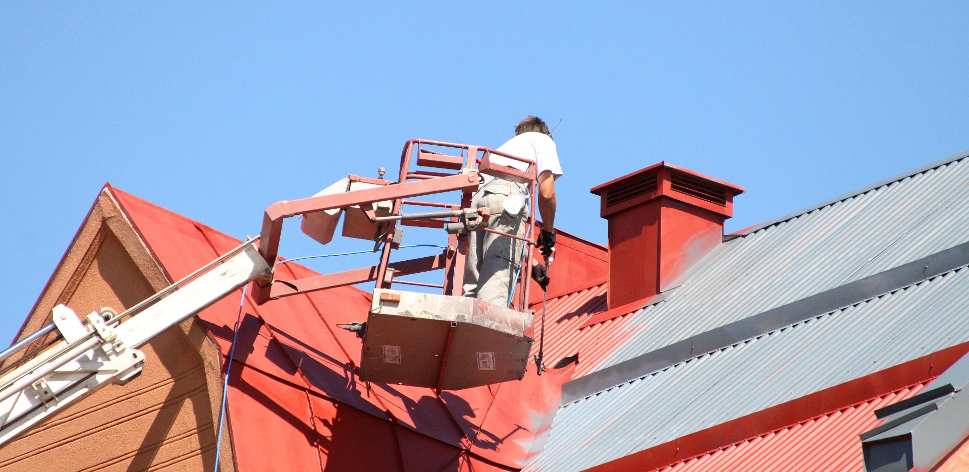 Mężczyzna na wysięgniku maluje dach